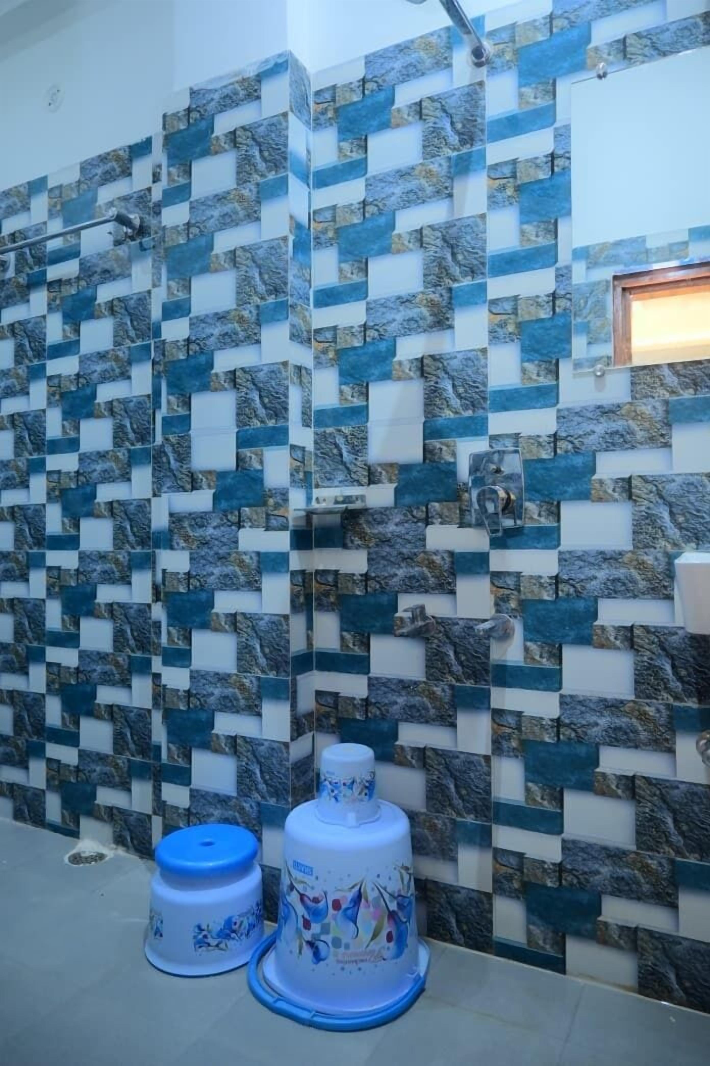 Ein Badezimmer mit Wand aus Mosaikfliesen und zwei weißen Behältern mit blauen Deckeln.