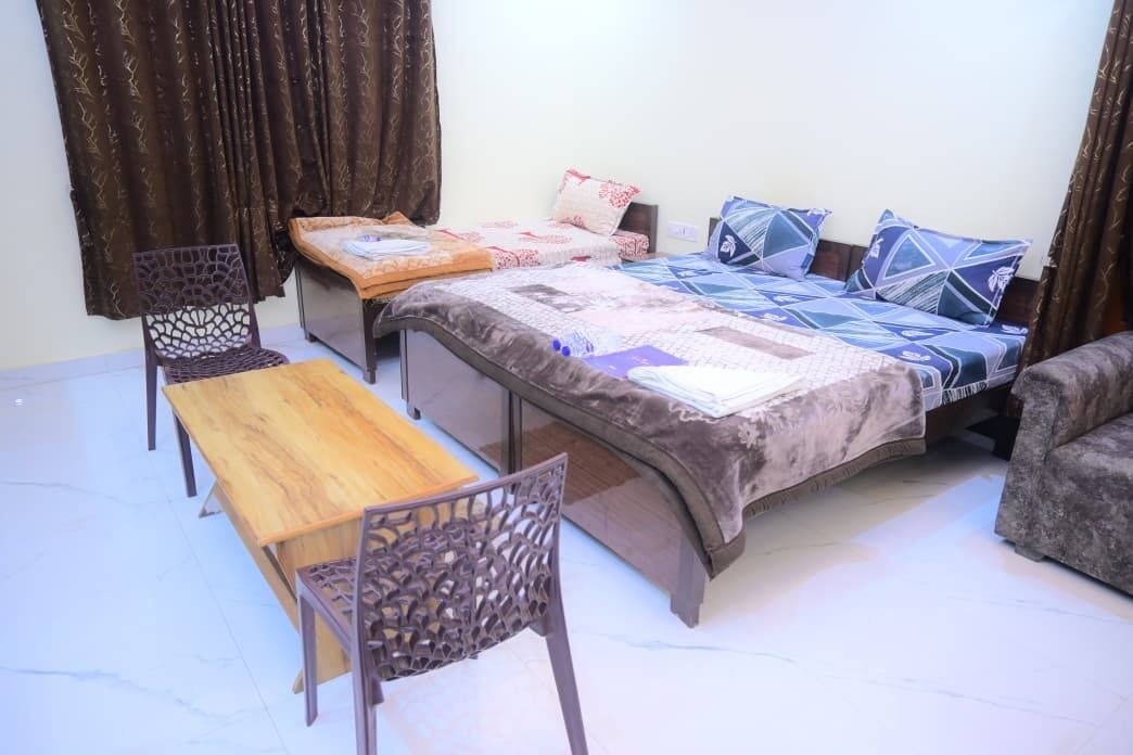 A bedroom with a bed, two chairs, a wooden table, and a small table.