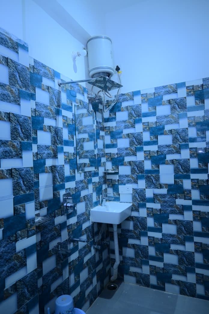 A bathroom with a sink, a white faucet, and a wall with a blue and white patterned tile design.