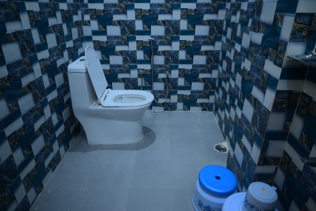 A bathroom with a toilet, a sink, and a tiled wall with a checkered pattern.