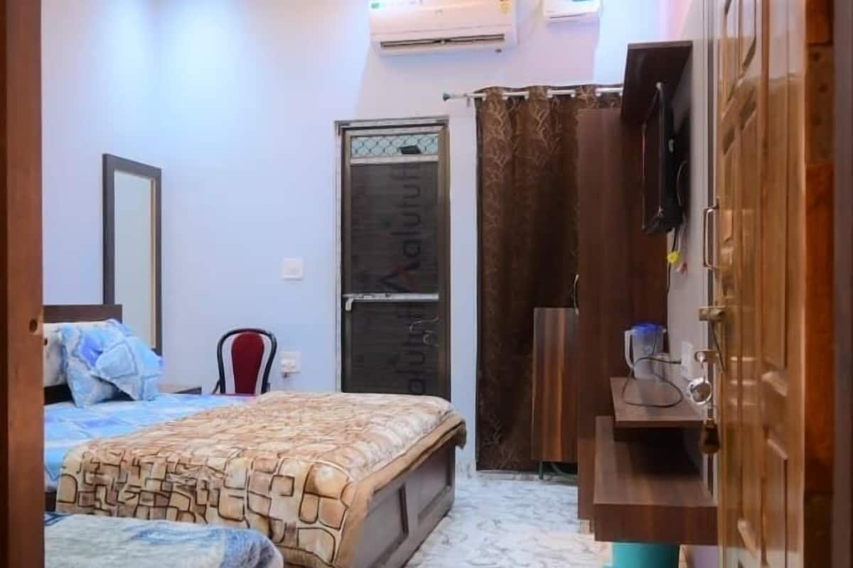 Un dormitorio con cama, ventilador de techo, aire acondicionado, televisor montado en la pared y armario.