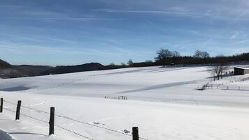 A snow-covered field with a fence, a building, and a clear sky.