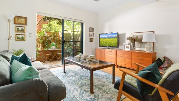 A living room with a sofa, a coffee table, a TV, and a wooden cabinet. - Spacious 2-Bed Townhouse with a Lush Courtyard (Erskineville)