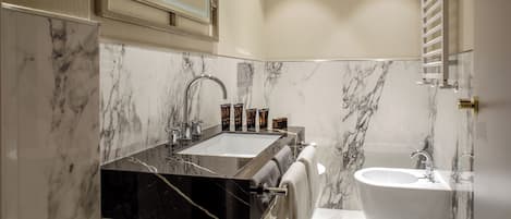 A bathroom with a marble sink, a bathtub, and a mirror above the sink.