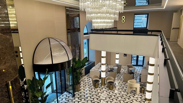 A spacious lobby with a modern chandelier, seating area, and a patterned floor. - Aria Palace by OMNIA Hotels (Rome)