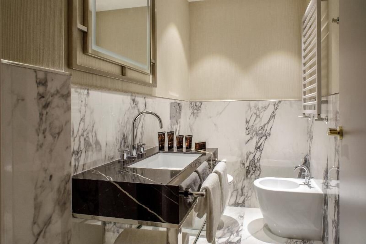 Une salle de bain avec un lavabo en marbre, une baignoire et un porte-serviettes.