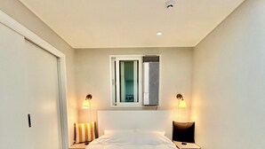 A neatly arranged bedroom with a large bed, two bedside tables, a window with blinds, and a ceiling light. - 5 mins to Unseo Station, the nearest to the Incheon Airport, Located in Cafe St. (Incheon)