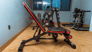 Ein Fitnessstudio mit Trainingsgeräten, darunter eine Bank und Gewichtsmaschinen.