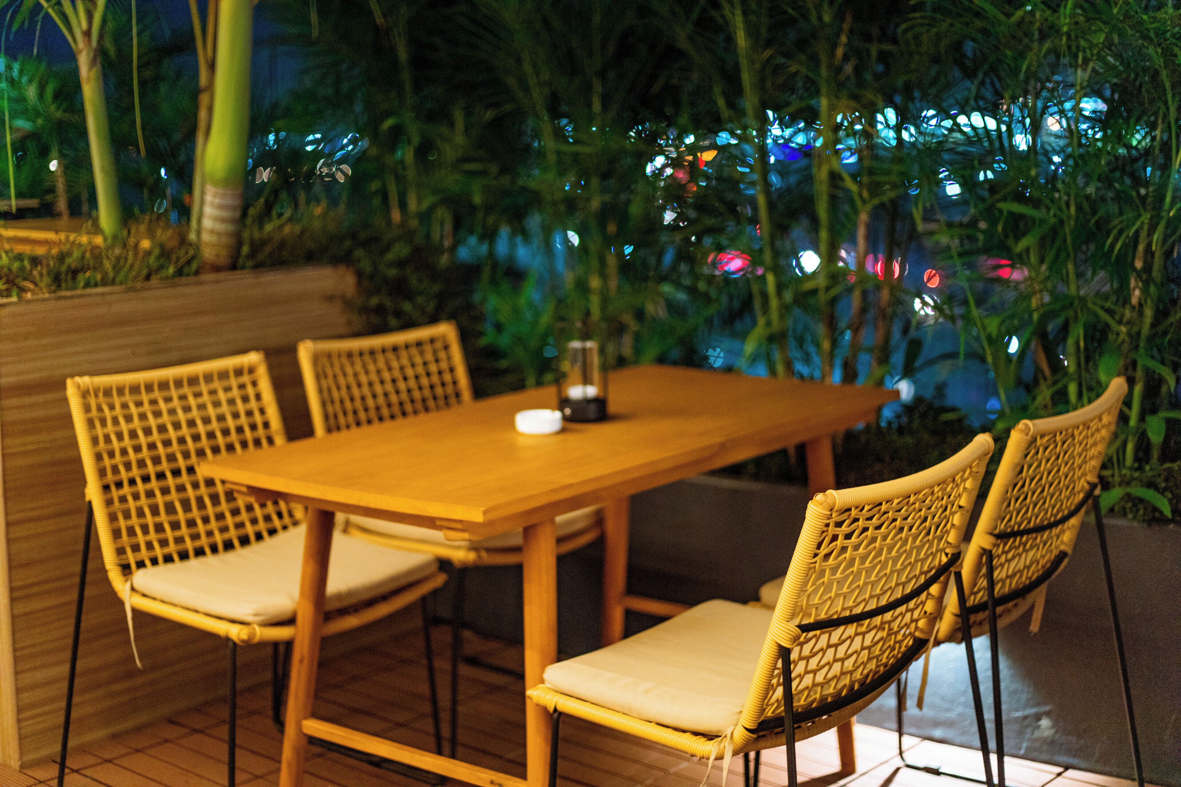 An outdoor dining area with a wooden table and wicker chairs.