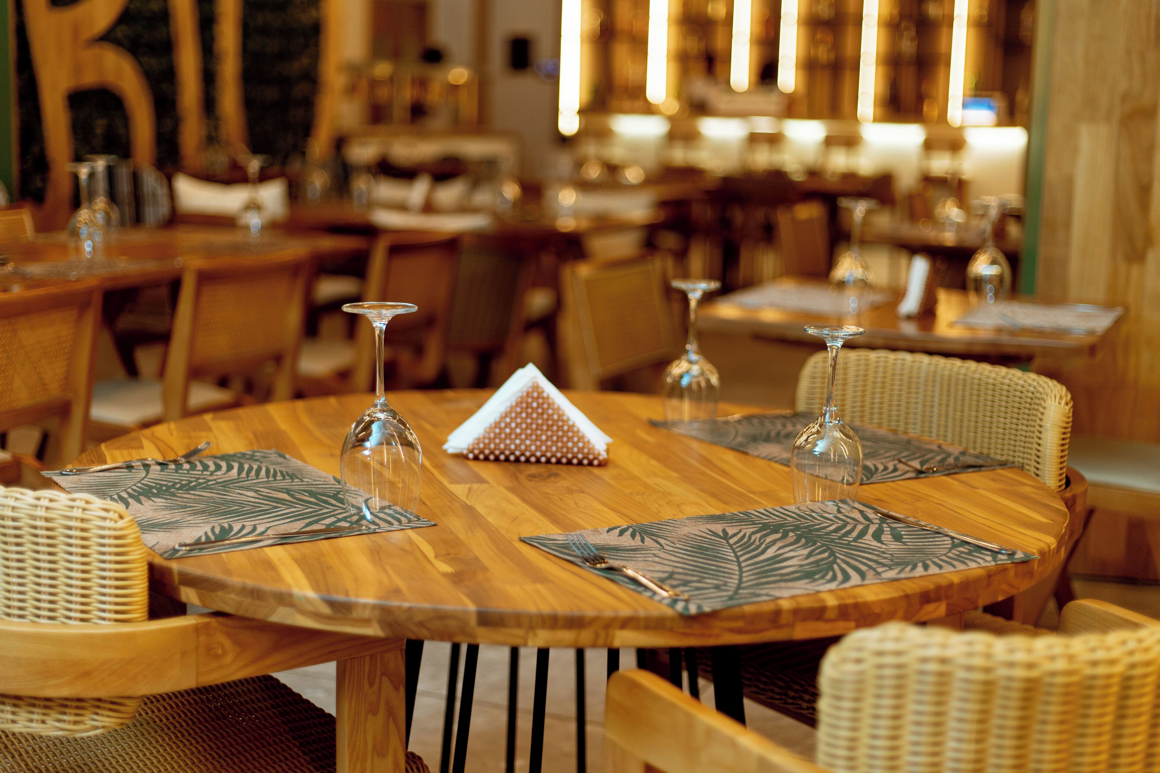 Een restaurantinterieur met ronde tafels, stoelen en transparante glazen.