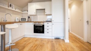 A modern kitchen with white cabinets, a microwave, an oven, and a wooden countertop. - Rocklands (No 11) | Elie (Elie)