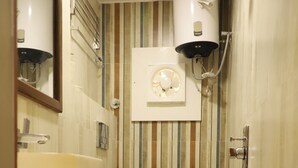 A compact bathroom with a toilet, sink, and a wall-mounted heater. - Hotel Hinduja Empire (Surat)