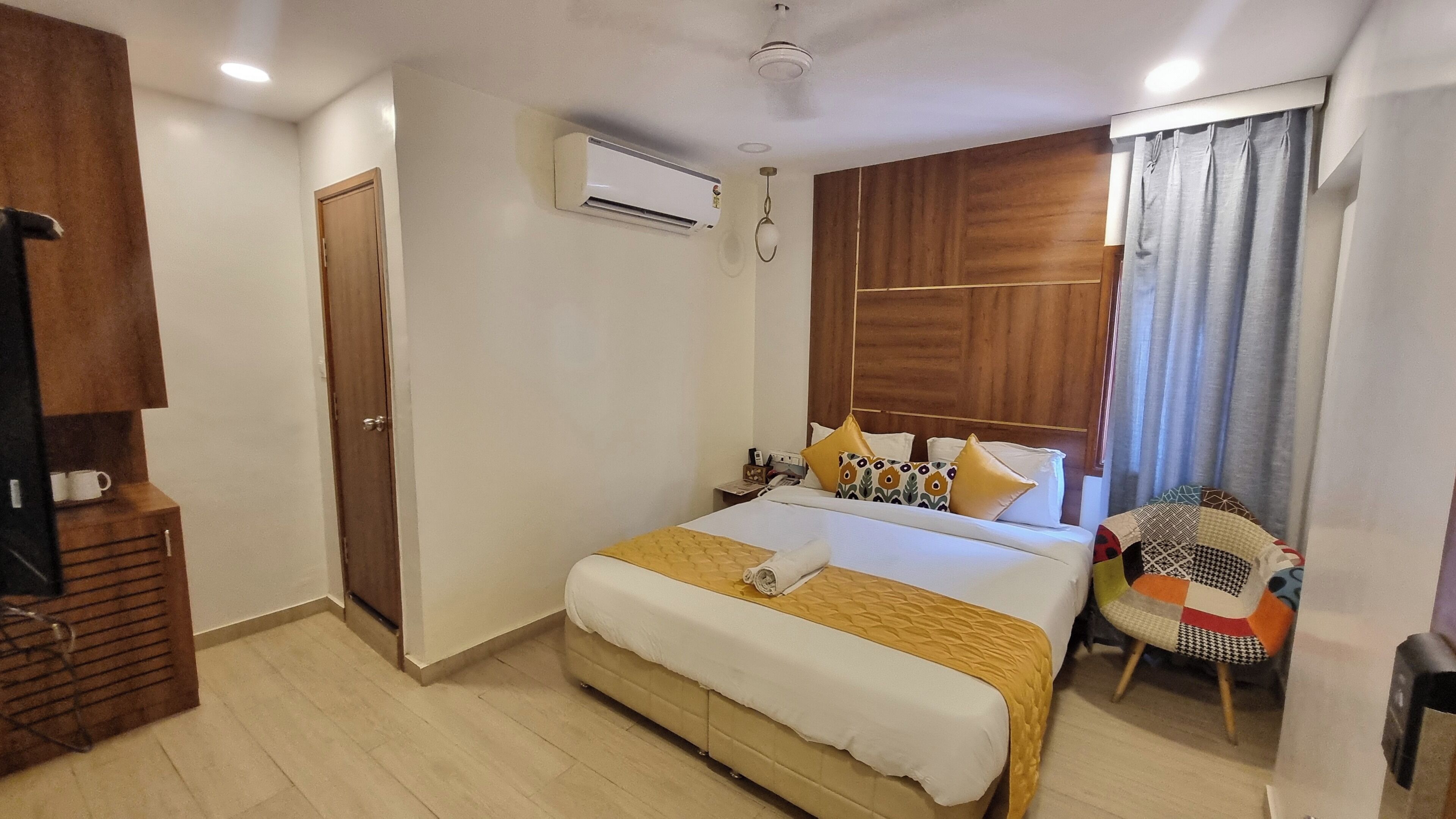 A hotel room with a large bed, wooden headboard, a small desk, and a chair.