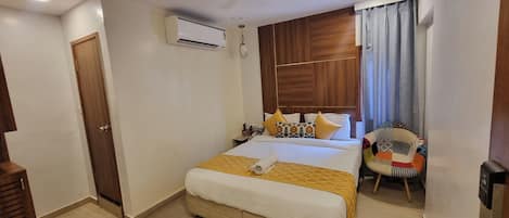 A hotel room with a bed, a wooden headboard, a small table, and a chair.