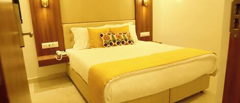 A hotel room with a large bed, a bedside telephone, and wall-mounted light fixtures.