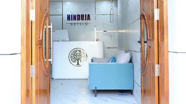A reception area with a wooden door, a reception desk, and a blue sofa. - Hotel Hinduja Empire (Surat)