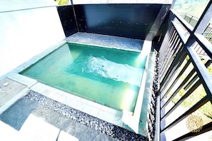A rectangular swimming pool with a stone border and a metal railing on one side.