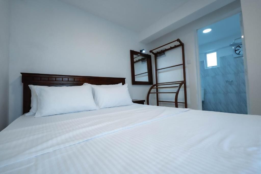 Ein Hotelzimmer mit Bett, Holz-Kopfteil, Spiegel und Duschbereich.
