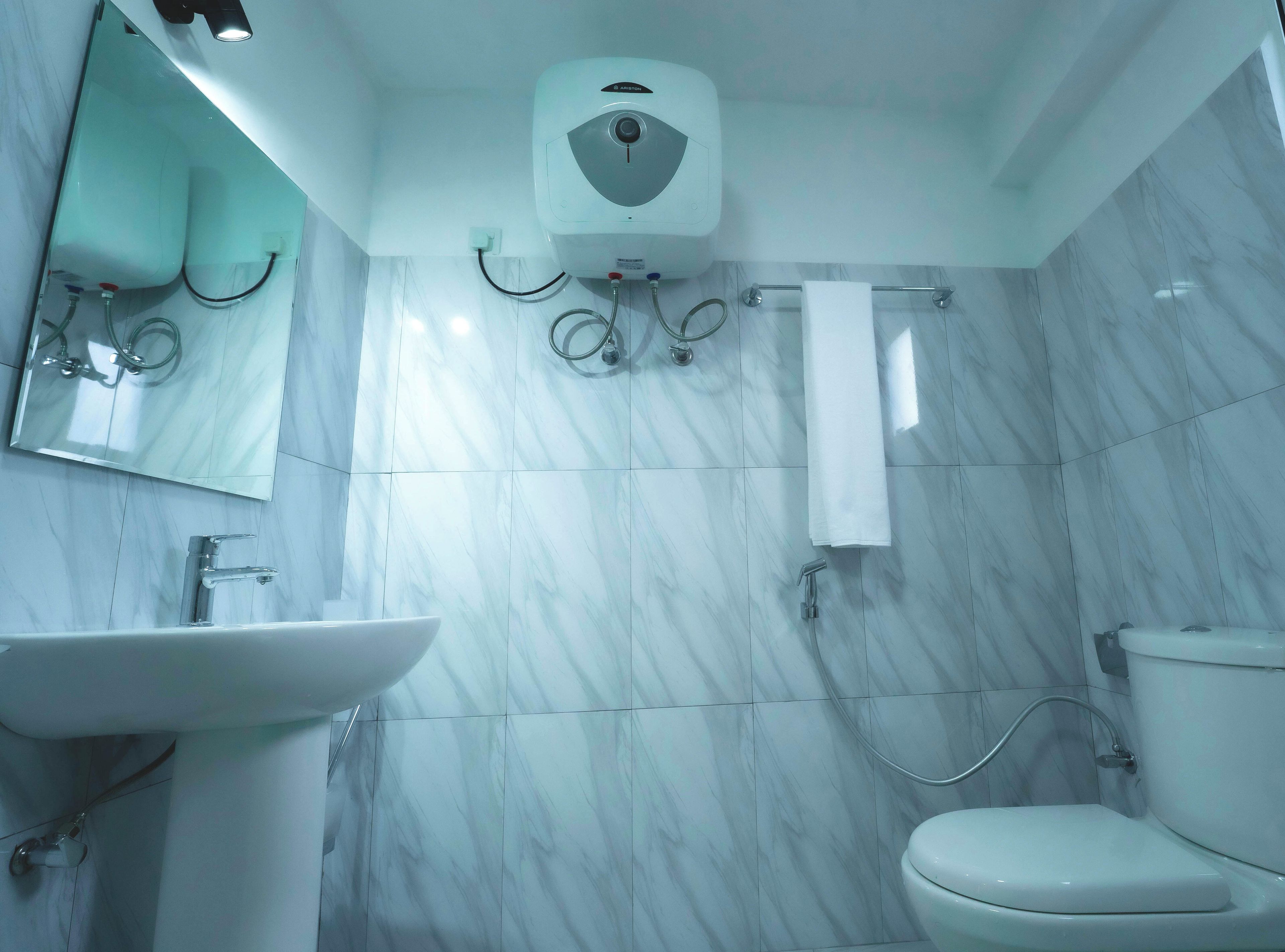 Un baño con un lavamanos blanco, un inodoro y un secamanos instalado en la pared.
