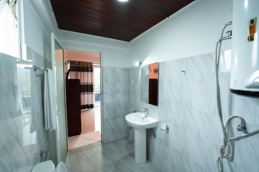 A modern bathroom with a glass shower enclosure, a pedestal sink, and a walk-in shower.