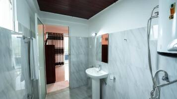 A modern bathroom with a glass shower enclosure, a pedestal sink, and a walk-in shower.