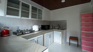 Una cocina moderna con armarios blancos, estufa, microondas y pileta.