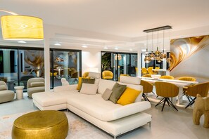 A modern living room with a sectional sofa, yellow chairs, and a dining area with a table and chairs. - Villa 'Beach-side 5B' with Private Pool, Private Terrace and Air Conditioning (El Paraíso)