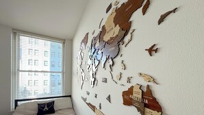 Un dormitorio con un gran mapa mundial en la pared, una cama con colcha estampada y una ventana con persianas.