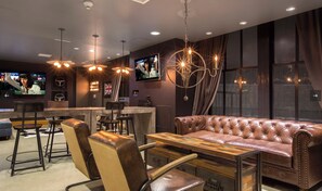 Eine Bar mit Ledersitzgelegenheiten, einem Holztisch und einem Fernseher, der eine Sendung zeigt.