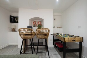 A room with two wicker chairs, a foosball table, and a dartboard on the wall. - Norfolk House - Steps from Quays, Parks & Docks (Gloucestershire)