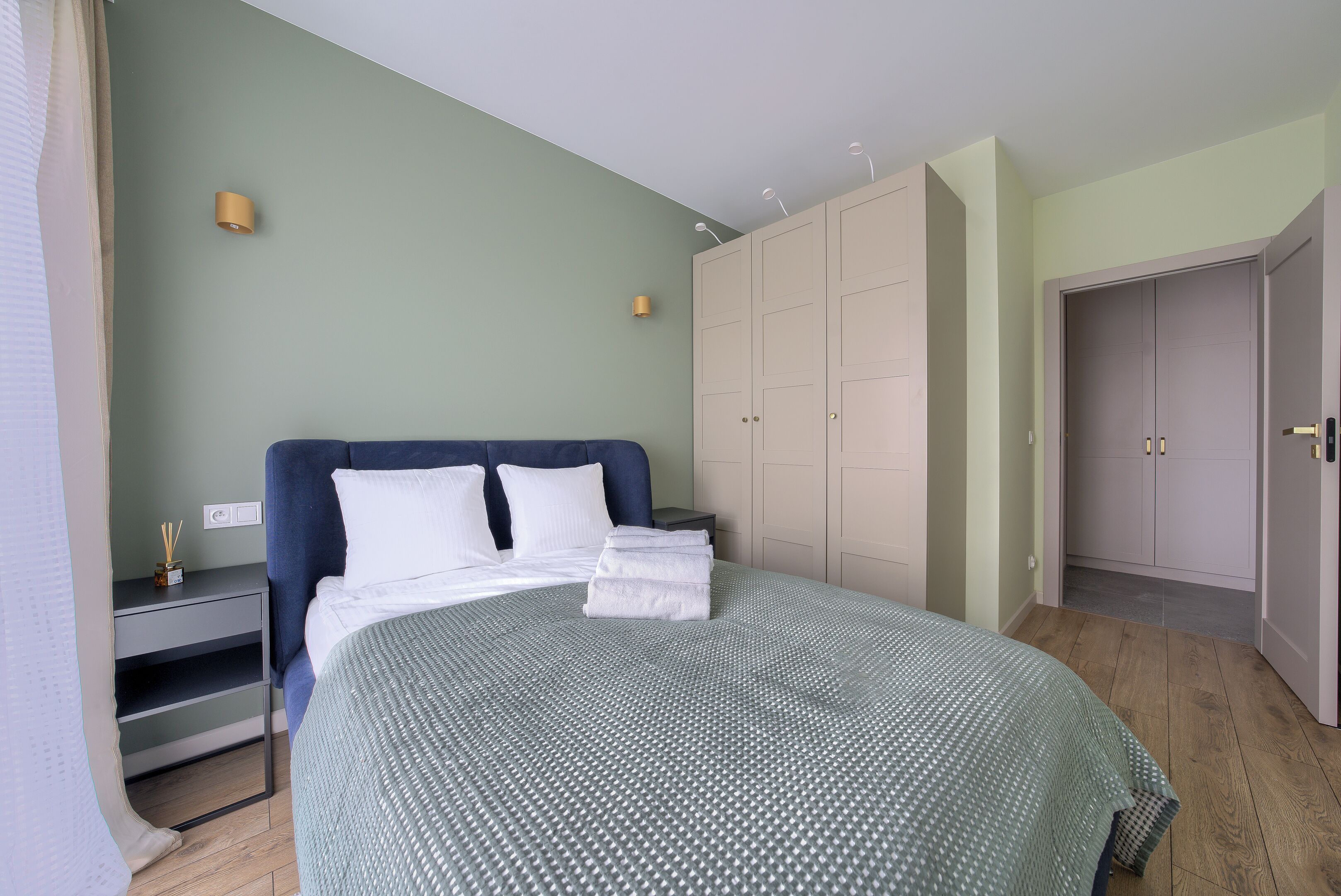A bedroom with a bed, a nightstand, a wardrobe, and a door.
