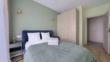 A bedroom with a bed, a nightstand, a wardrobe, and a door.