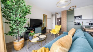 A modern living room with a blue sofa, yellow armchair, and a large potted plant. - Apartamenty Sun & Snow Nad Odrą (Szczecin)