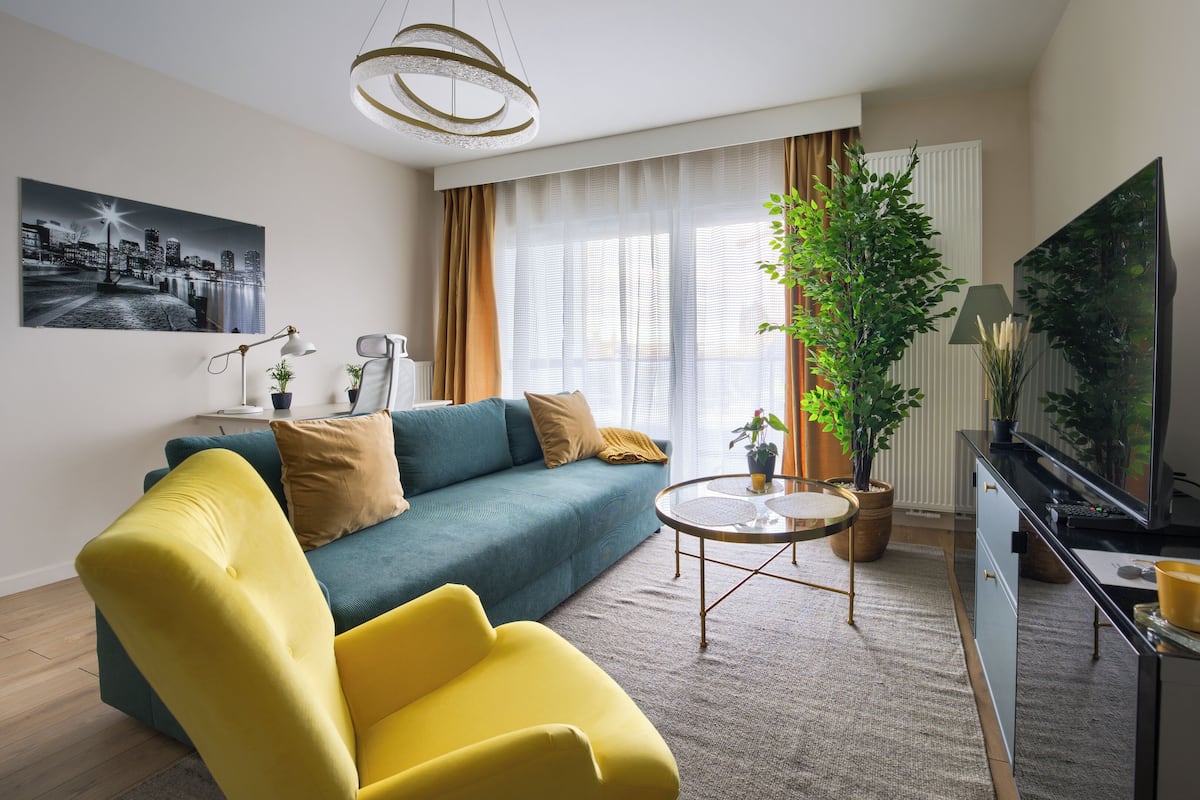 Una sala de estar moderna con un sofá, un sillón amarillo y una mesa de centro redonda.