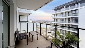 A balcony with a view of a cityscape, a table, and two chairs. - Apartamenty Sun & Snow Nad Odrą (Szczecin)