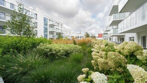 Un immeuble d’habitation moderne doté de balcons et d’un jardin aménagé avec des hortensias.