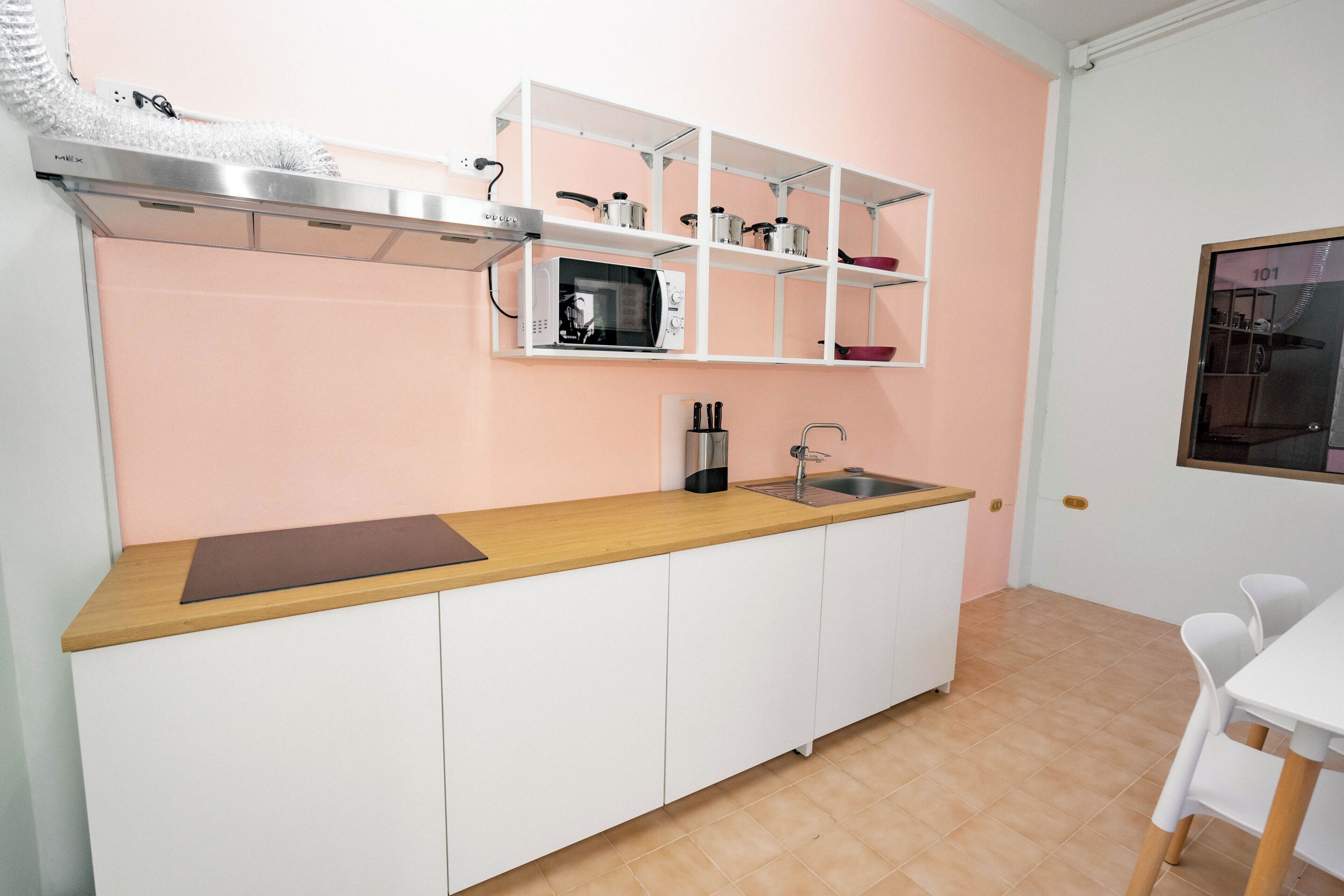 A compact kitchen with white cabinets, a microwave, a sink, and a wooden countertop.