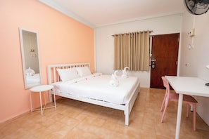 Une chambre à coucher avec un lit, une table de chevet, une chaise, un miroir, une porte et un ventilateur.