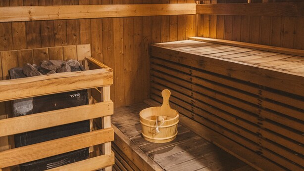 A sauna with wooden benches and a wooden bench with a bucket. - Pink Residence Chalong (Rawai)