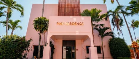 Um edifício com uma placa indicando 'PINK RESIDENCE' e um design arquitetônico moderno.