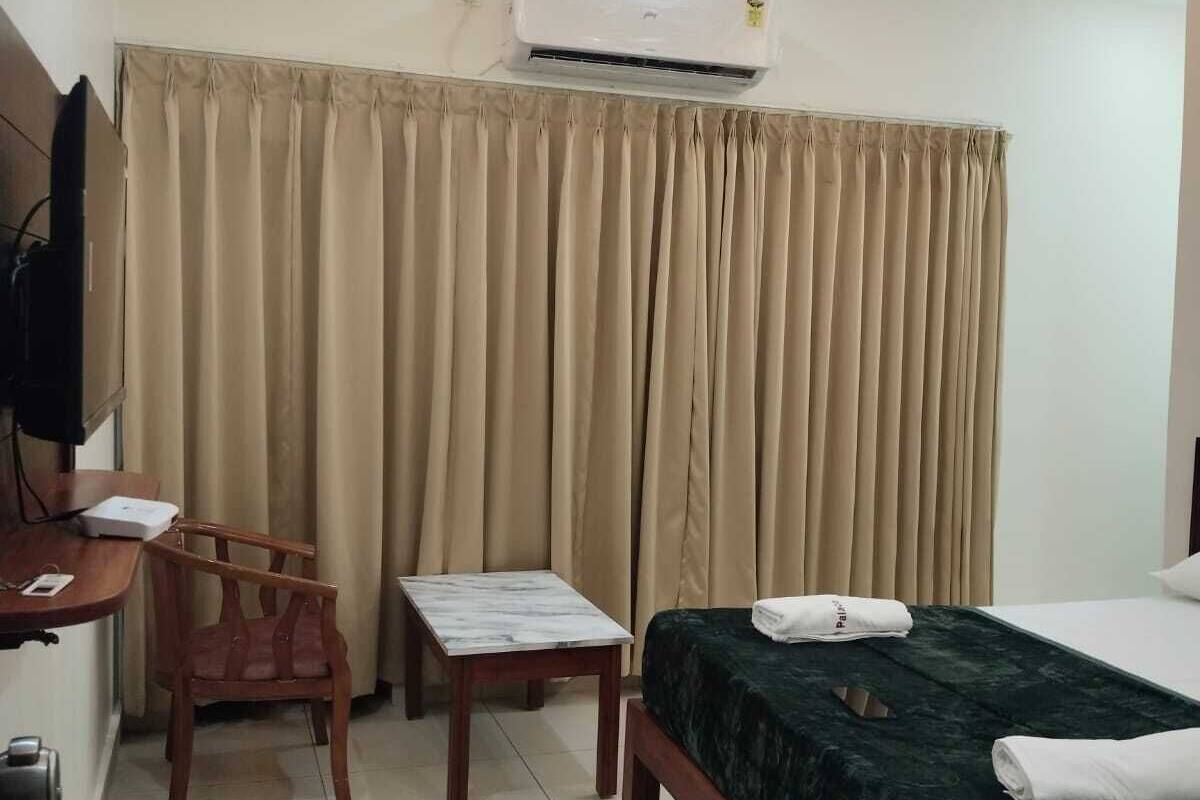 Une chambre d’hôtel équipée d’un lit, d’un bureau, d’une chaise, d’une télévision et d’un appareil de climatisation.