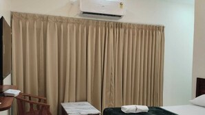 Une chambre d’hôtel comprenant un lit, un bureau avec une chaise, une petite table et un appareil de climatisation.