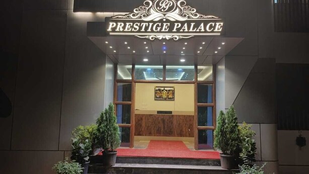 L’entrée du Prestige Palace est agrémentée d’un tapis rouge, de plantes en pot et d’une enseigne placée au-dessus des portes.