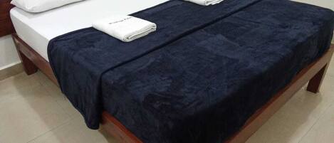 A neatly made bed with a dark blue bedspread and white pillows.