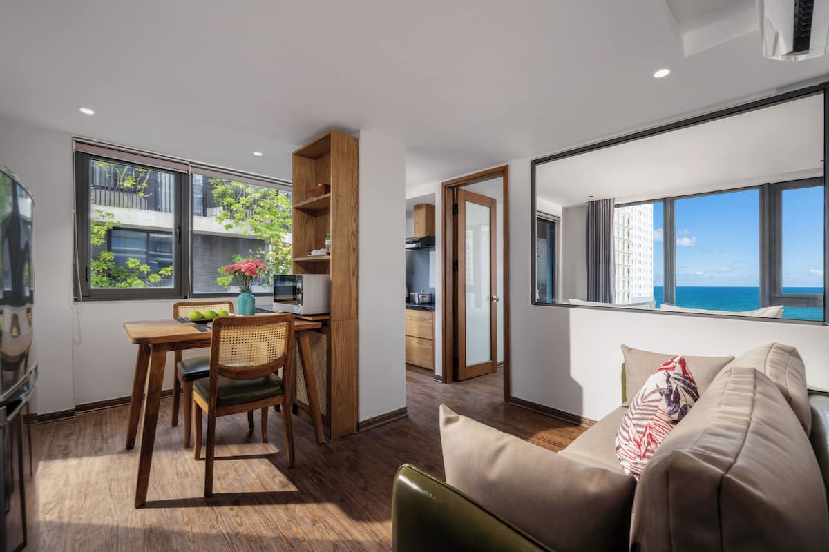 Een moderne woonkamer met een groot raam, een bank en een eetgedeelte met een tafel en stoelen.