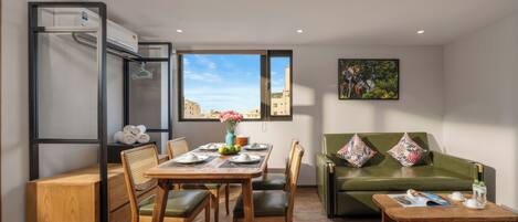 A compact living space with a dining area, a sofa, and a window with a city view.