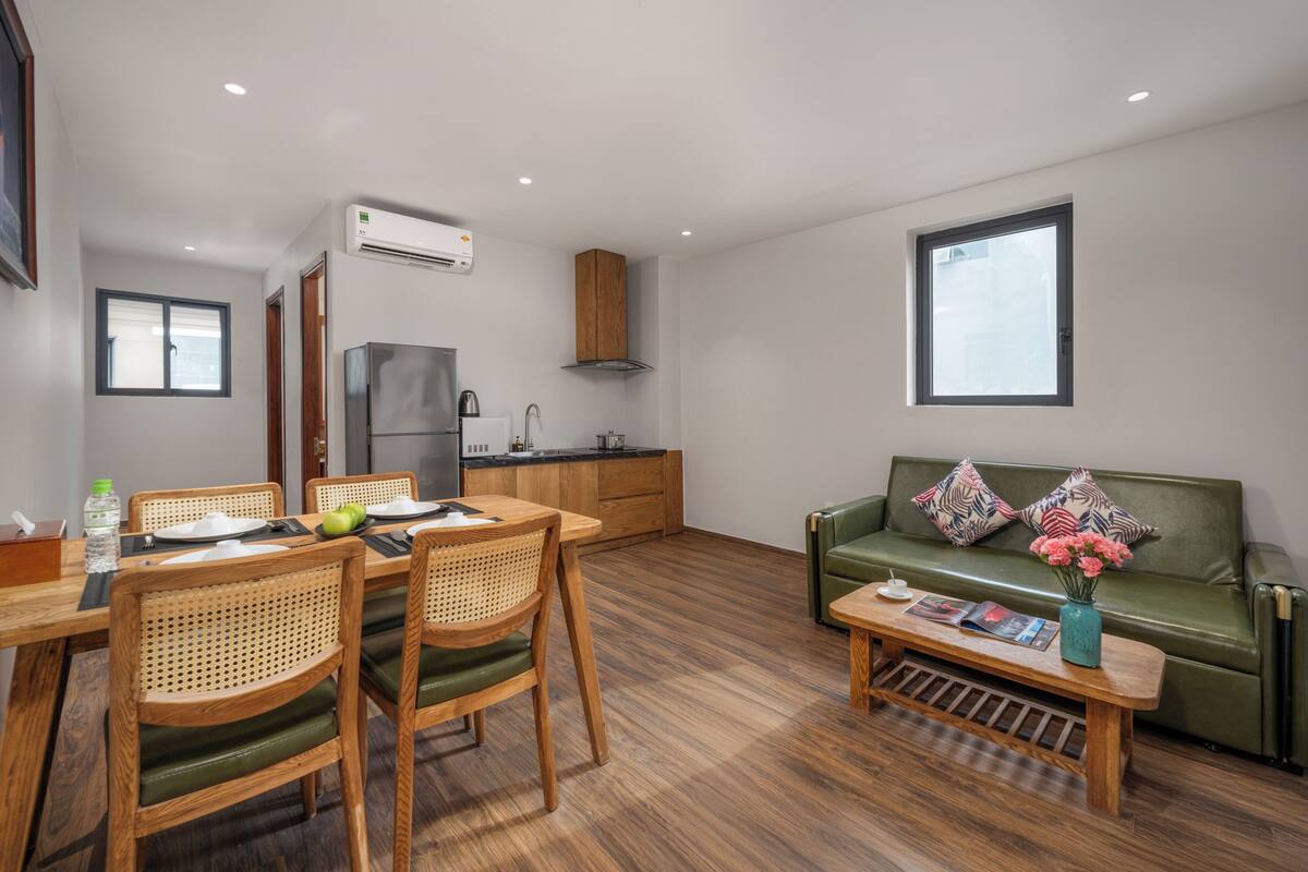 Een moderne woonkamer met een eethoek, een bank en een keuken op de achtergrond.
