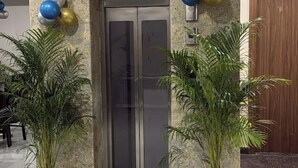 A marble-floored lobby with a double door, potted plants, and balloons. - Hotel Divines Residency  (Noida)