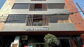 A building with a sign reading "Divine's Residency." It features a modern architectural design with a combination of brick and glass elements. - Hotel Divines Residency  (Noida)
