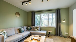 Een woonkamer met een bank, salontafel en een klok aan de muur.